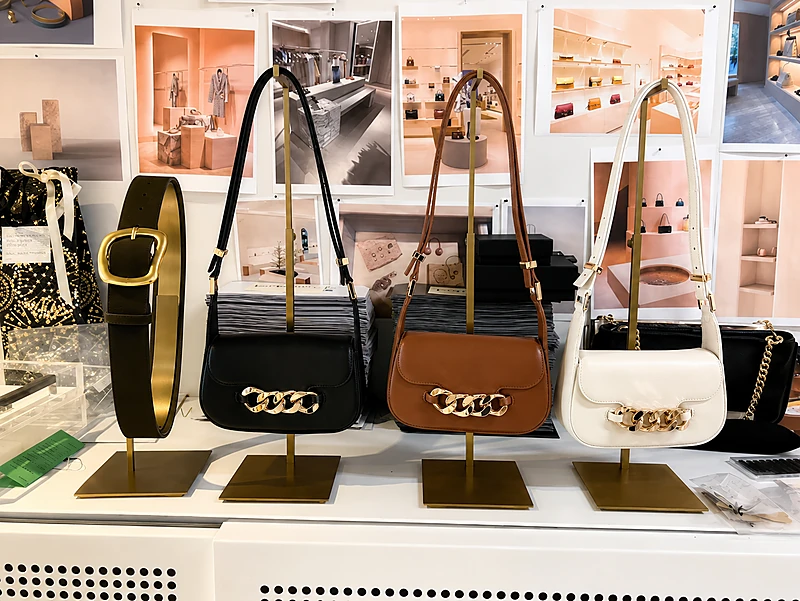 Client-installed custom metal handbag display stands in a retail store